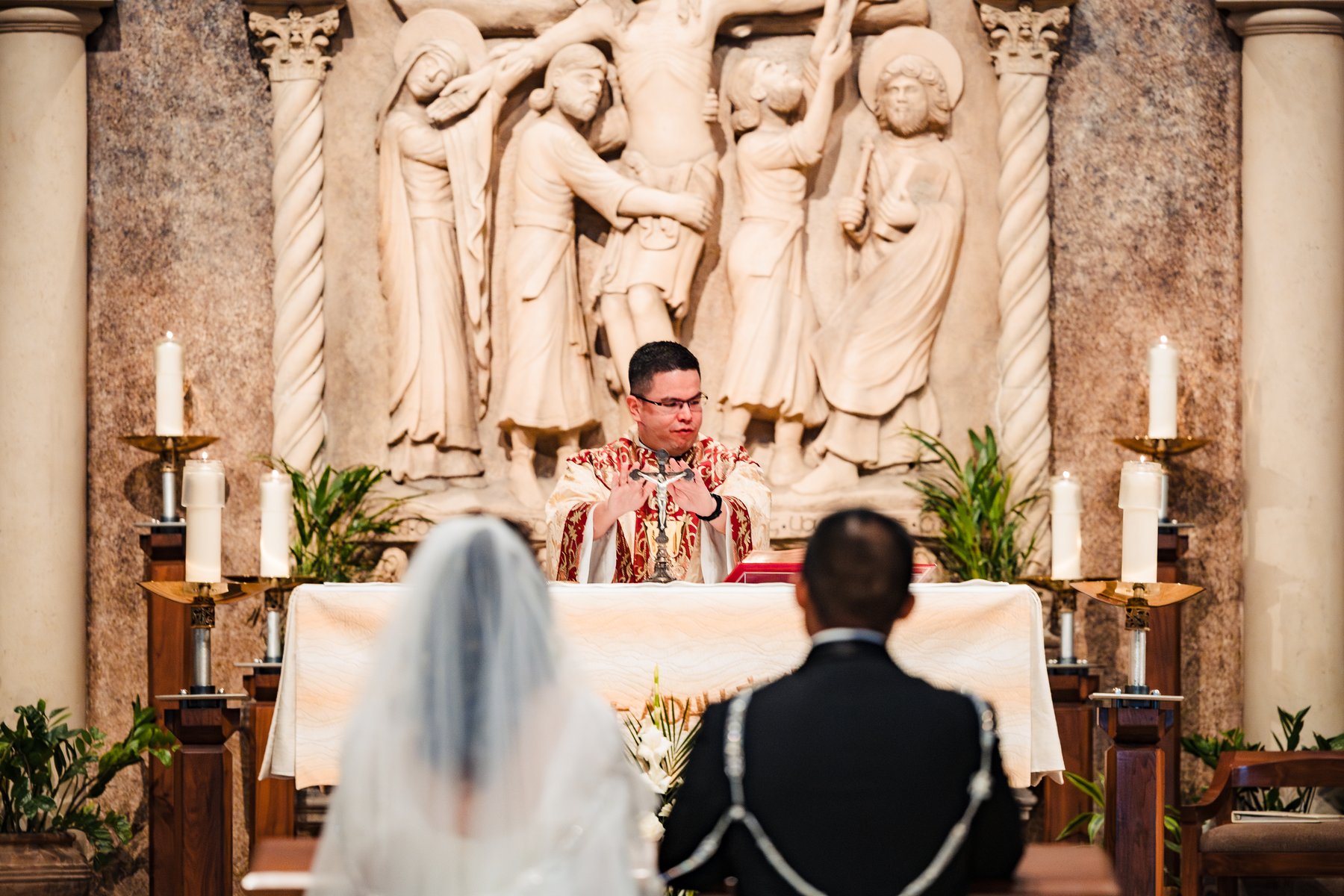 The consecration during the Nuptial Mass — the priest elevating the crucifix at St. Martha's in Murrieta