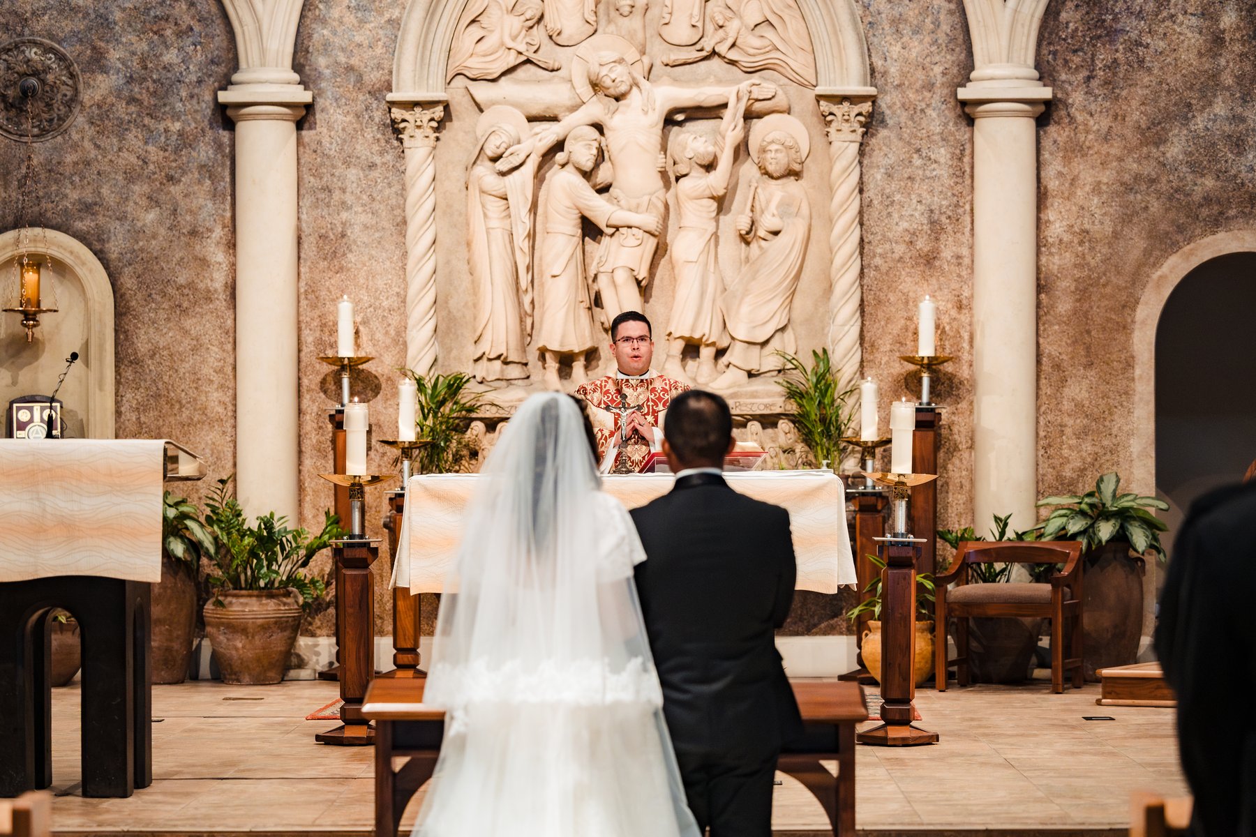 The couple kneeling before the priest at the altar during the Nuptial Mass in the Inland Empire