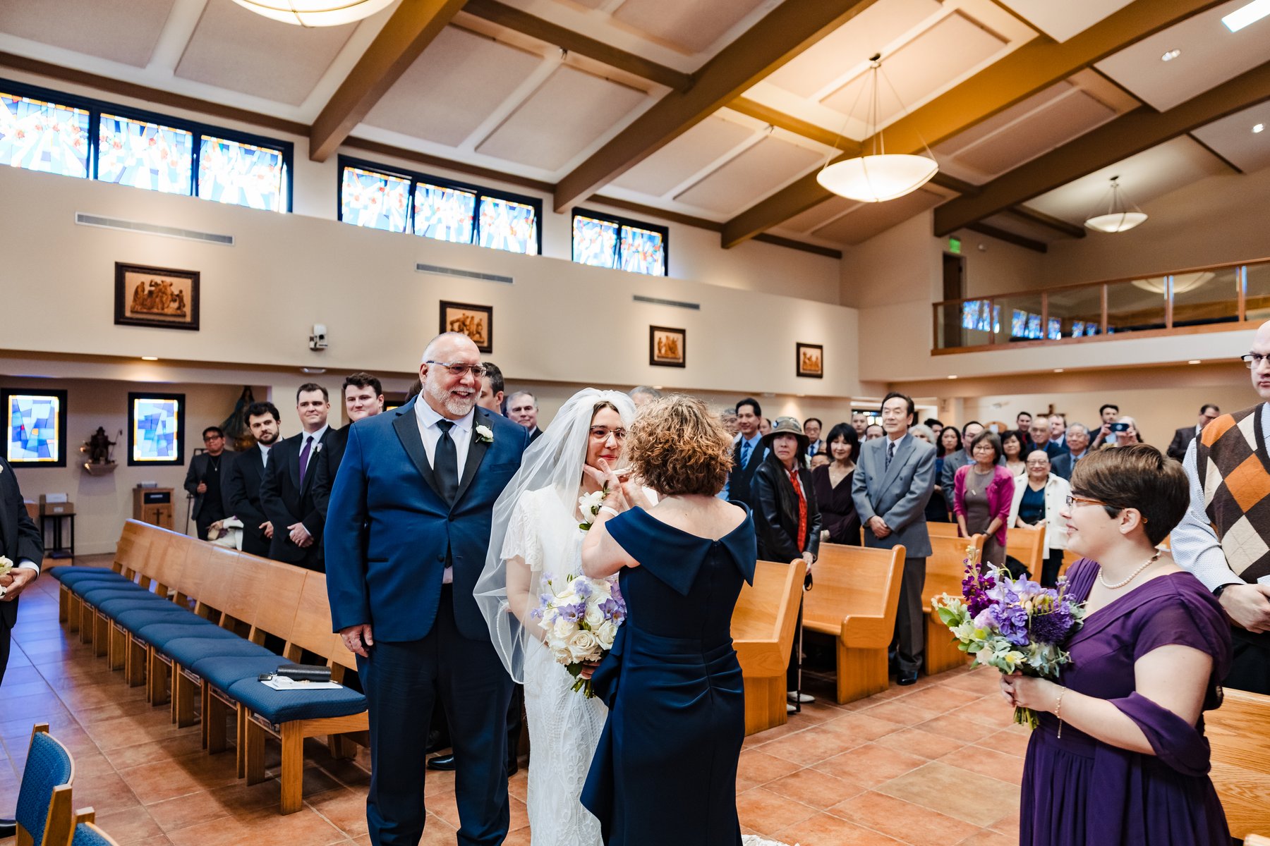 Bride entering the wedding with both parents as her mother adjusts her veil