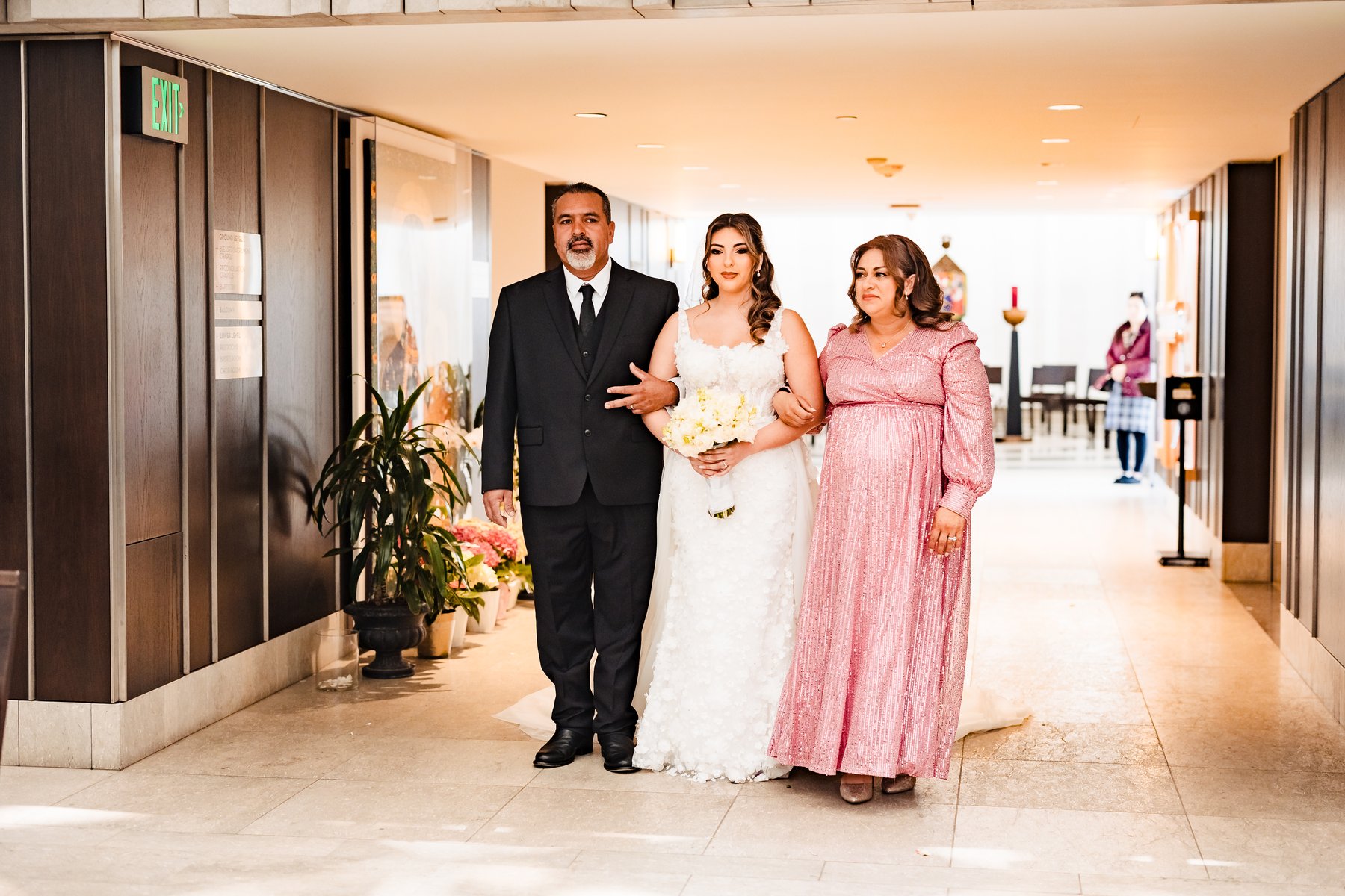 The bride entering the wedding accompanied by both parents at Christ Cathedral