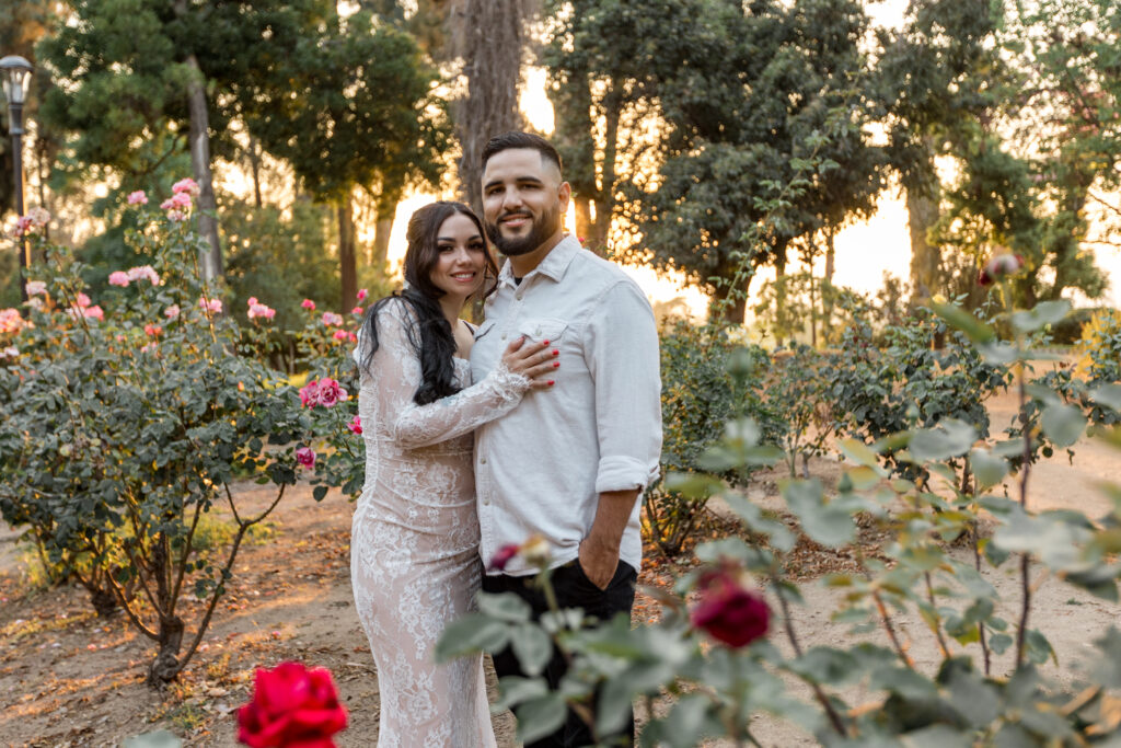 engaged couple standing with roses in Prospect park Redlands during sunset