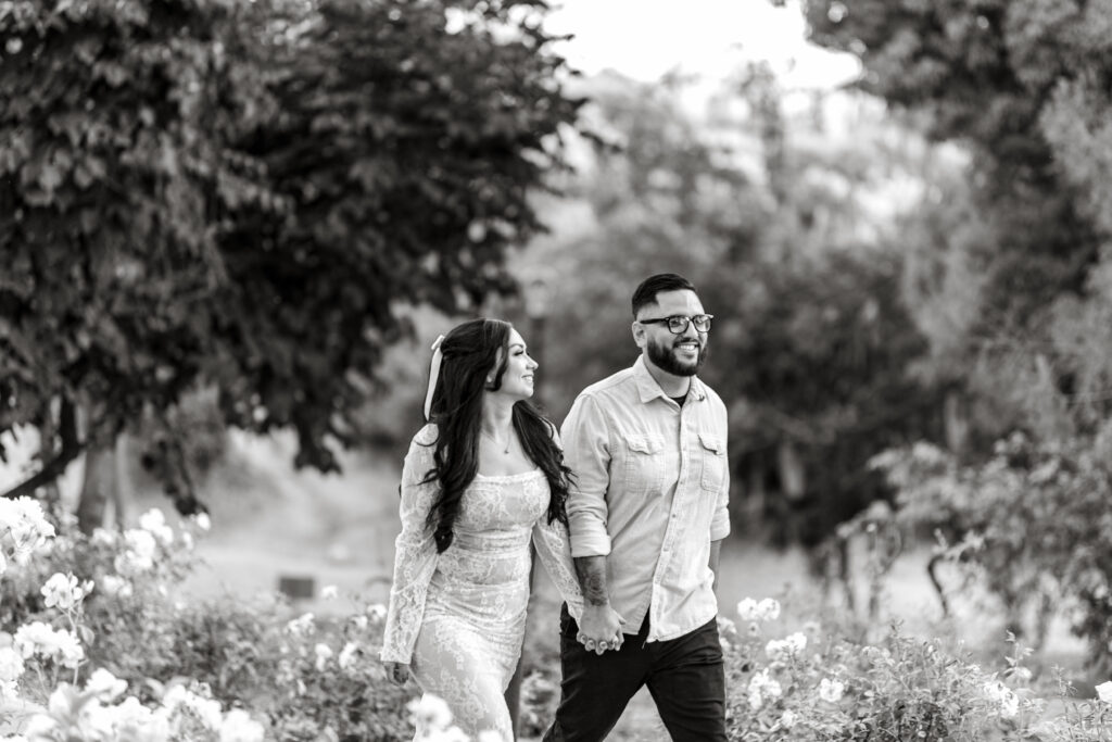 Black & White photo of couple holding hands walking thru redlands prospect park