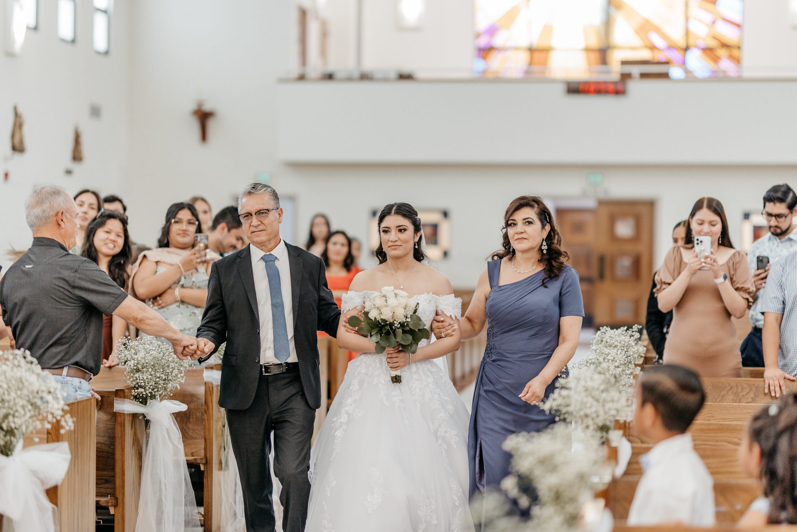 A father and mother walking their daughter down the isle for her wedding