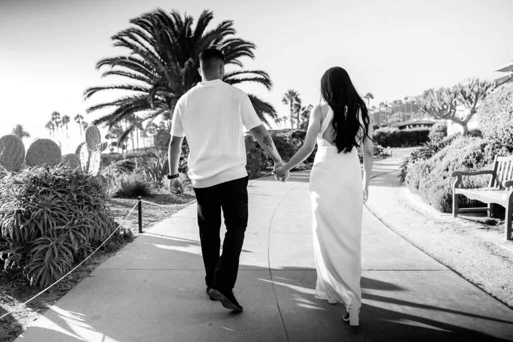 Black and white portrait of couple at engagement session holding hands Treasure Island - Laguna Beach