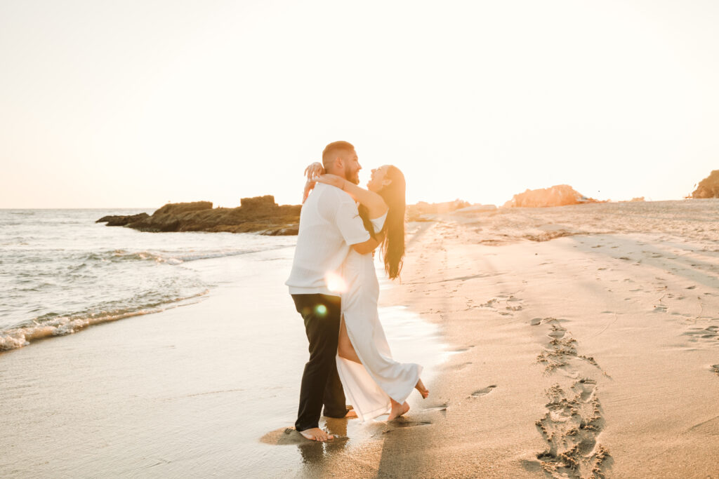 Engaged couple dancing on shore of Laguna beach