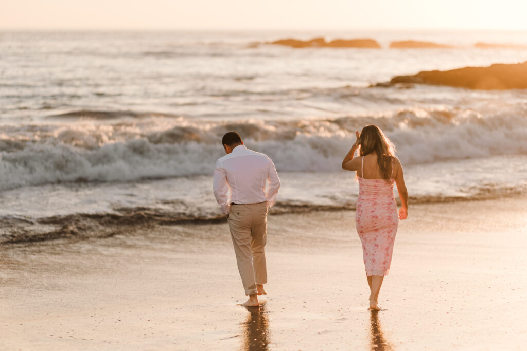 engaged couple walking on the shore in laguna beach