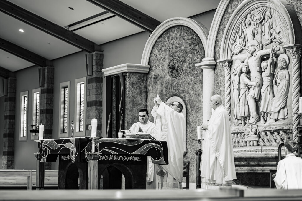 Priest lifting up the Eucharist during the consecration at the altar inside Saint Martha’s Catholic Church, Murrieta