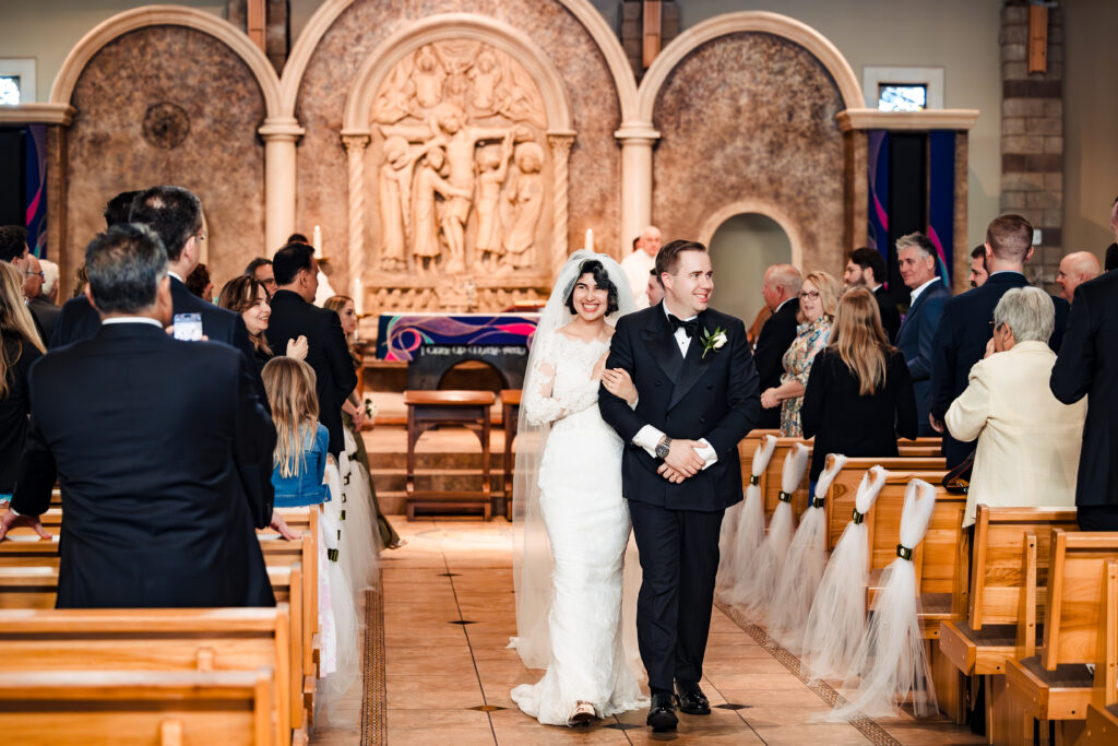 Newlywed couple walking down the aisle joyfully at Saint Martha’s in Murrieta, California