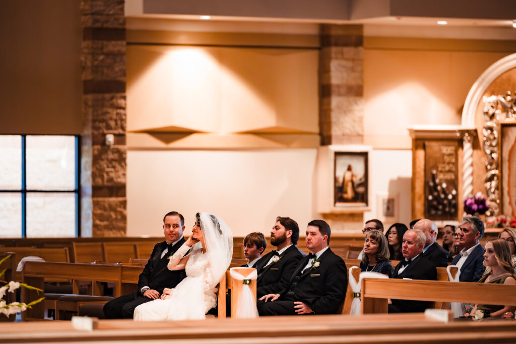 Bride and groom seated at altar during Catholic wedding ceremony at Saint Martha’s Church in Murrieta, CA