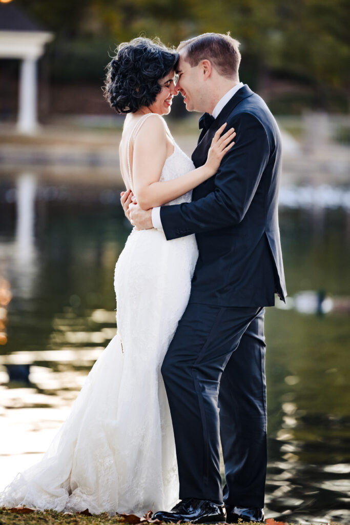 Joyful couple holding each other by the water after Saint Martha’s Church wedding