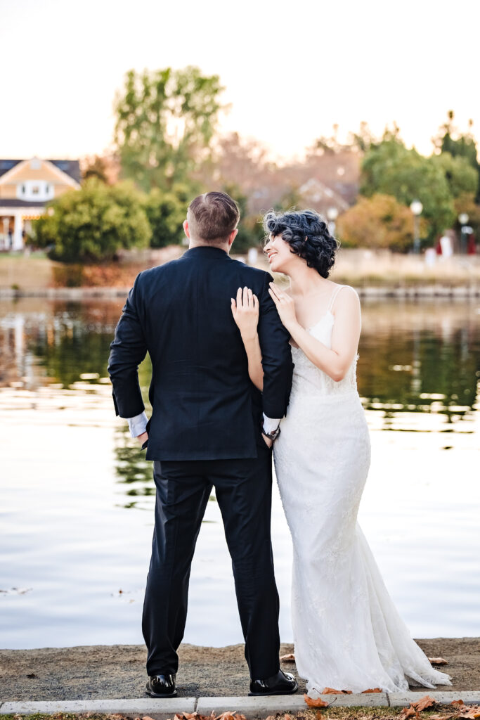 Playful bride and groom share quiet moment lakeside after Catholic wedding in Murrieta