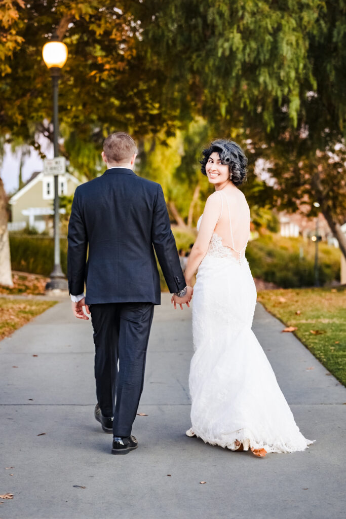 Couple walking hand in hand through park at golden hour after Catholic church wedding