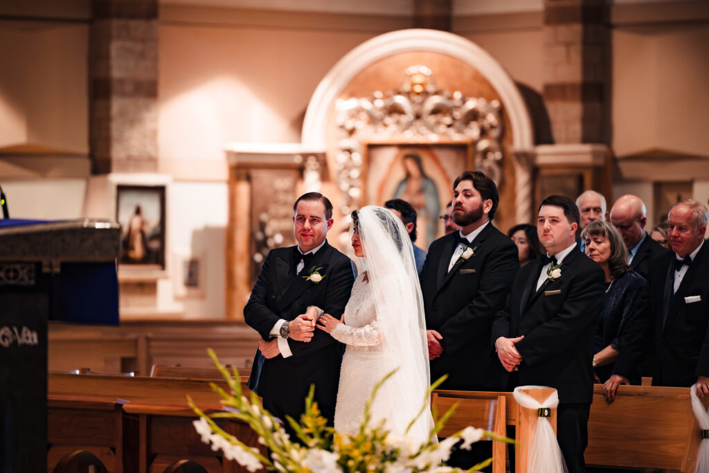 Bride standing with groomsmen at altar during Catholic nuptials in Murrieta church