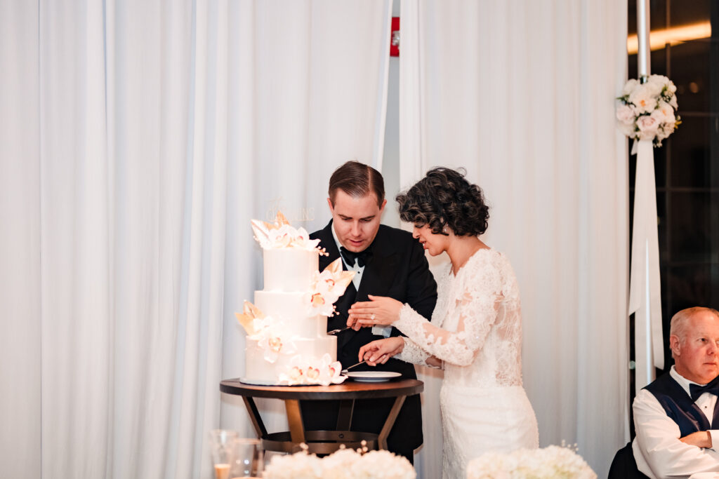 Bride and groom cutting their floral wedding cake at reception after Catholic wedding ceremony