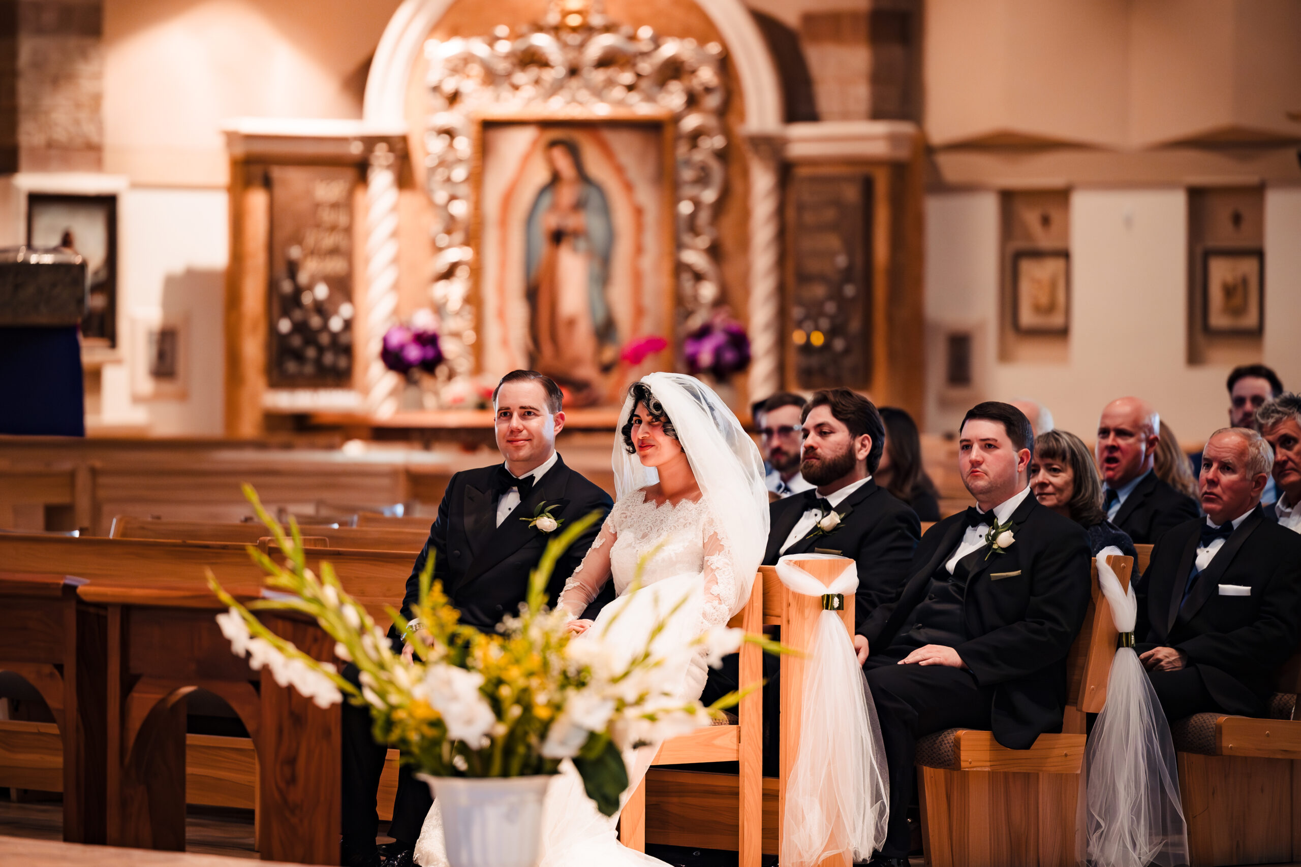Bride and groom seated at altar during Catholic wedding ceremony at Saint Martha’s Church in Murrieta, CA