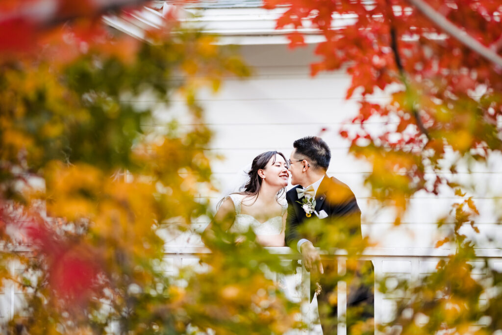 Fall leaves in foreground. Bride and groom together