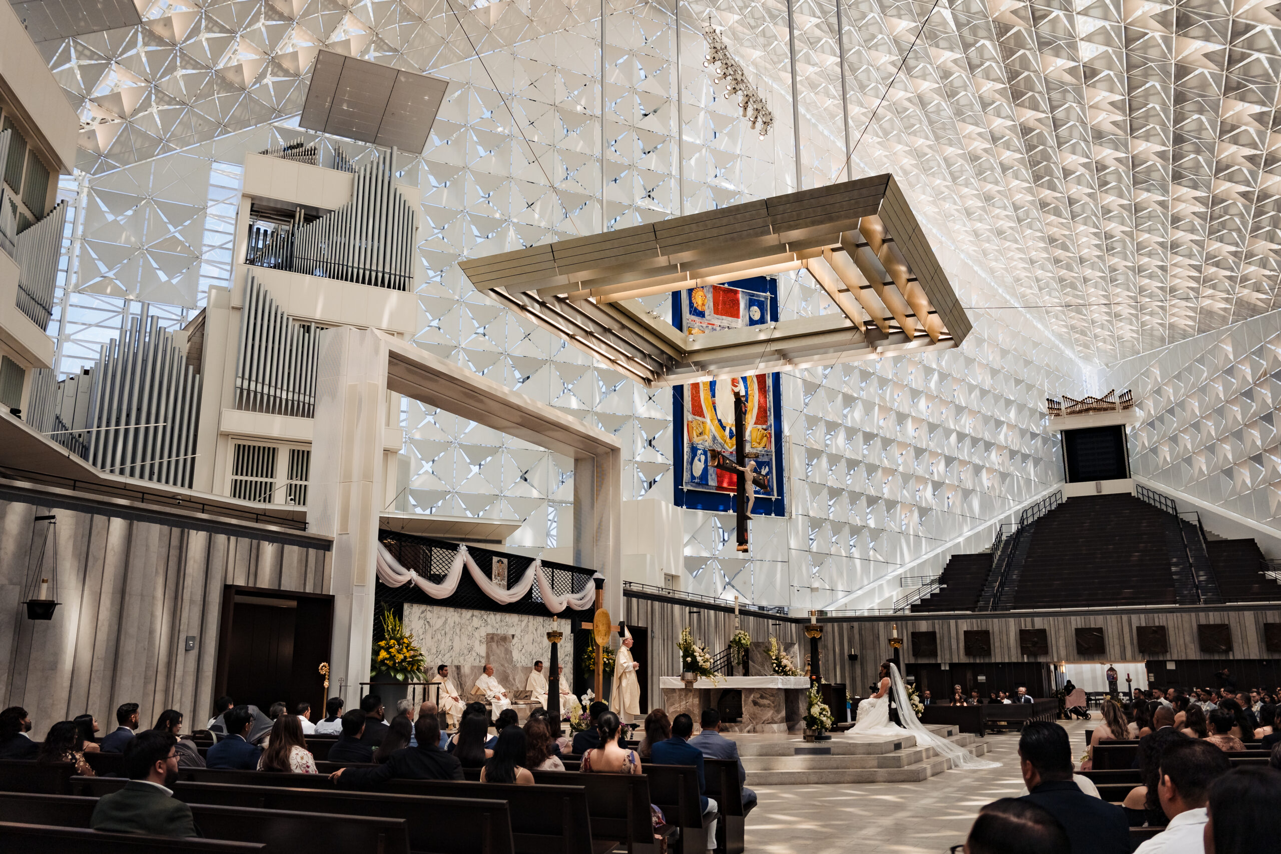 Wide angle interior view of a Catholic wedding ceremony at Christ Cathedral featuring the Hazel Wright Organ and the glass ceiling structure.