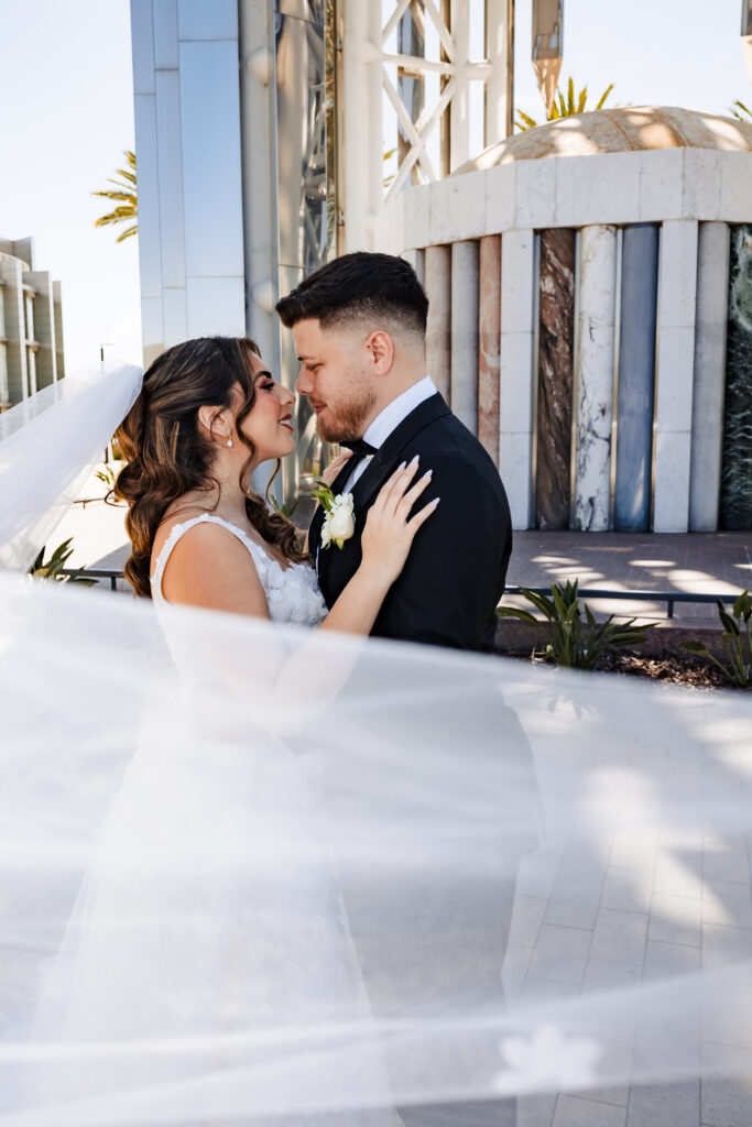 Romantic bride and groom portrait at Christ Cathedral featuring a dreamy veil overlay and modern architecture background.